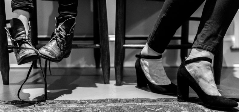 black and white photo of two sets of feet in shoes: one set of a child and one set of an adult