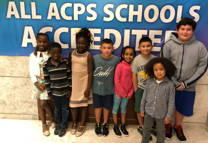 students smiling in front of accreditation banner