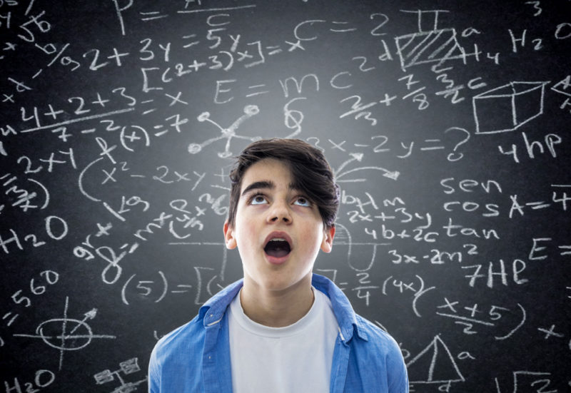 a boy with a bewildered face in front of a blackboard with math equations