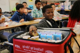 Middle school student reaching in bag for breakfast in the classroom item