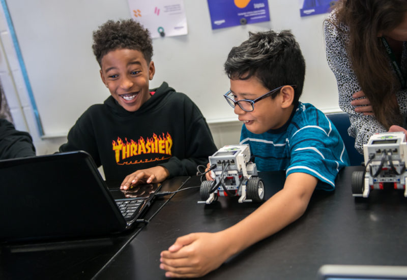 Two male students are surprised by what they can do to control their robot