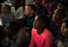 a black female student sits in a crowd of classmates in beautiful light