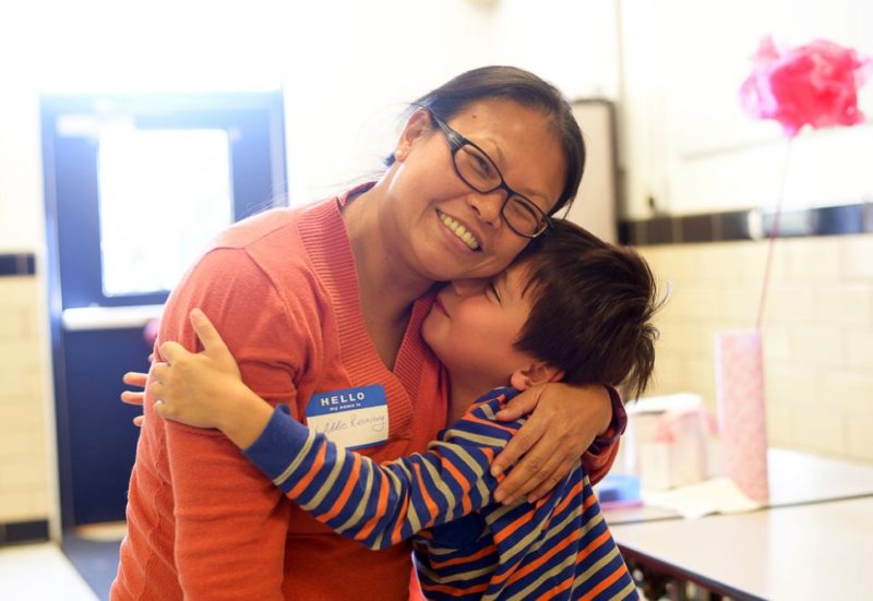 child hugging parent volunteer in school