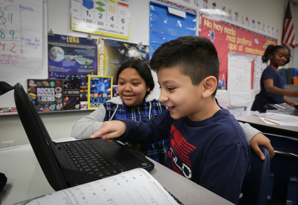 two students laughing around a computer