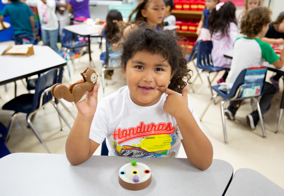 a young girl wearing a Honduras t-shirt holds up a plastic squirrel from a counting game