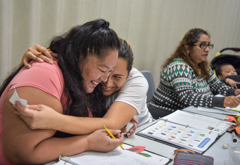 a woman hugs her friend while learning Enghlish