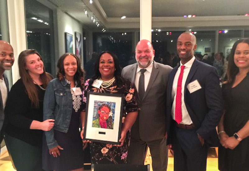 Pierrette Peters stands with her award surrounded by friends and colleagues