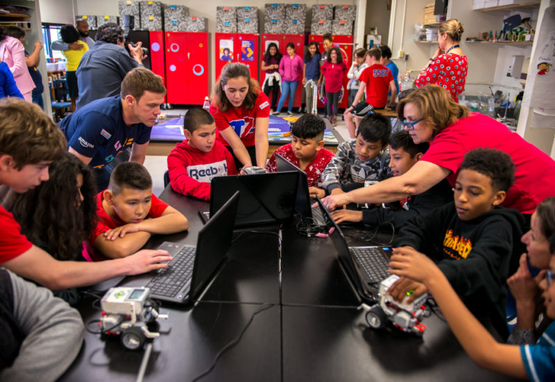 TC Williams High School robotics team students show Cora Kelly fifth graders how their robots are controlled on their laptops