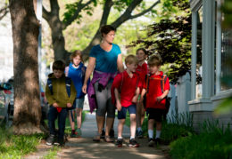 Adult female walking down a sidewalk with a group of students