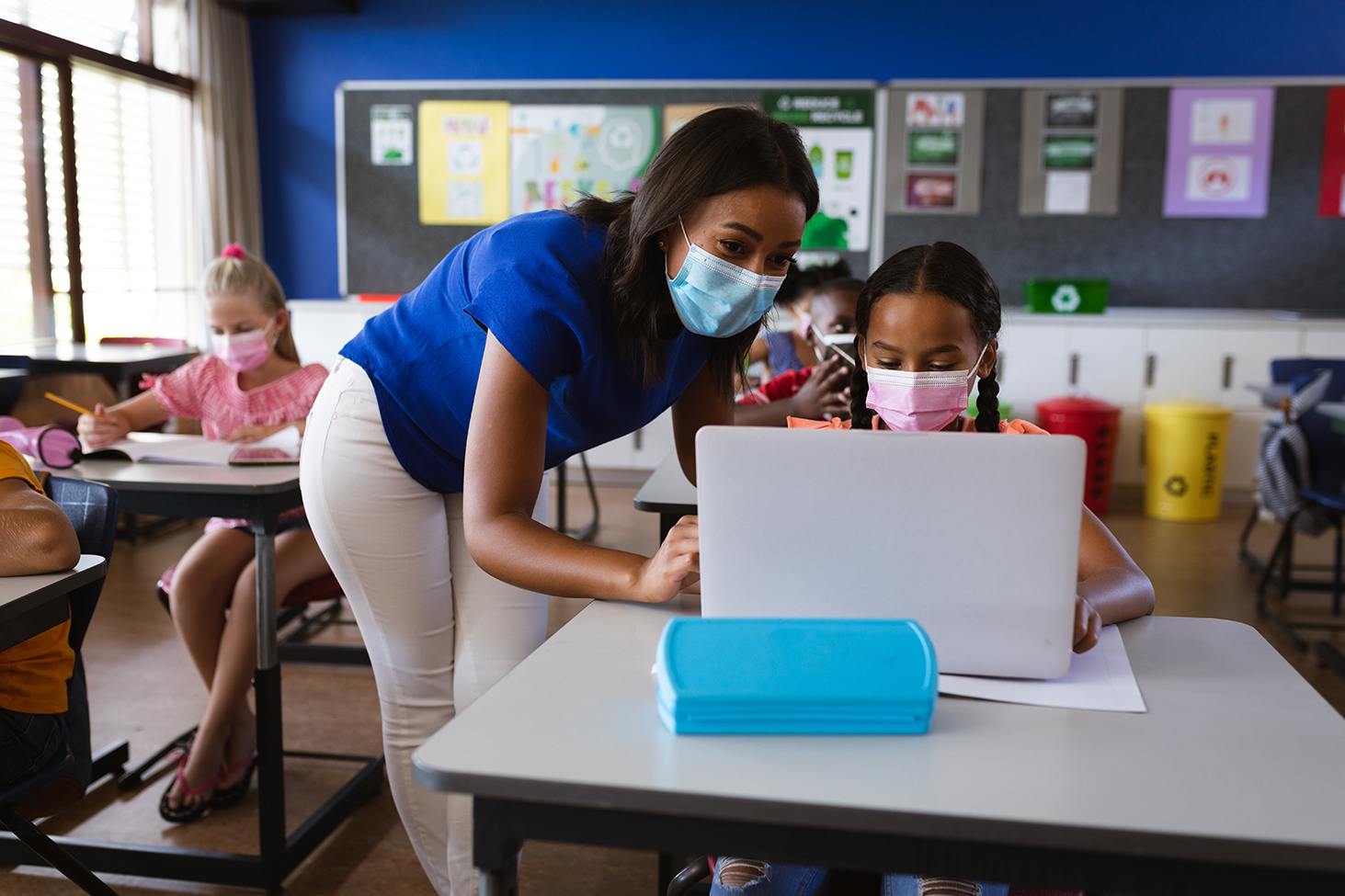 African American female teacher wearing face mask teaching a girl