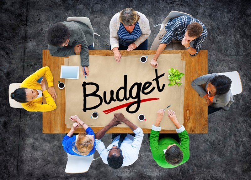 Aerial view of poeple round a table that says 'budget'