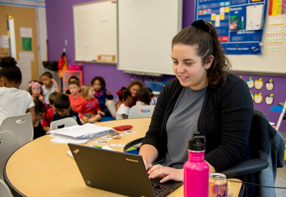 Teacher working at laptop in classroom