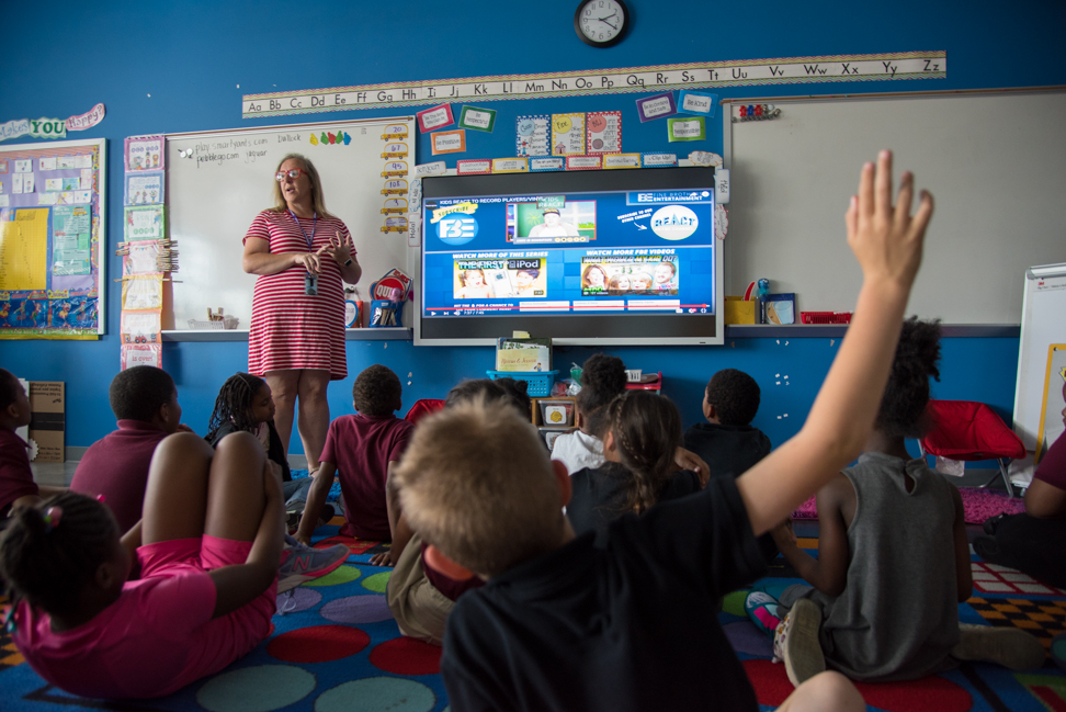 Teacher at front of classroom full of students