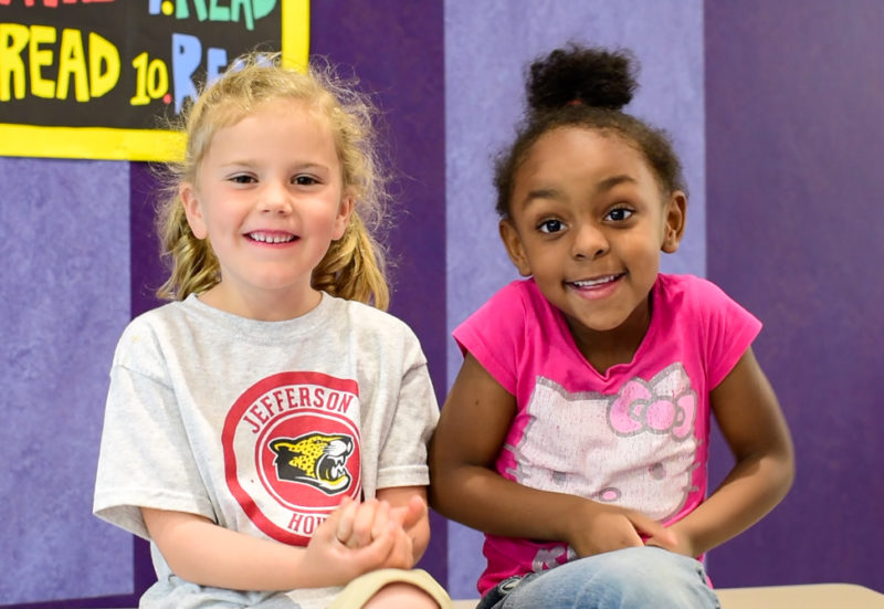 Two kindergarten girls giggle as they explain why you should take 2020 survey
