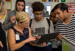 T.C. students looking at teacher's laptop