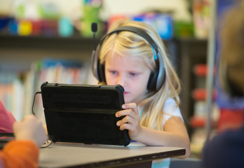 elementary school girl using tablet in classroom