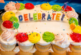 cake surrounded by cupcakes that say celebrate