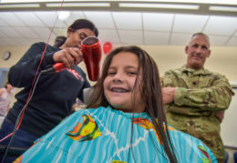 A father watches as a TC Williams cosmetology student dries his daughter's hair