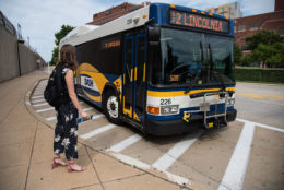 A woman awaits the doors of a DASH bus to open so she can board.