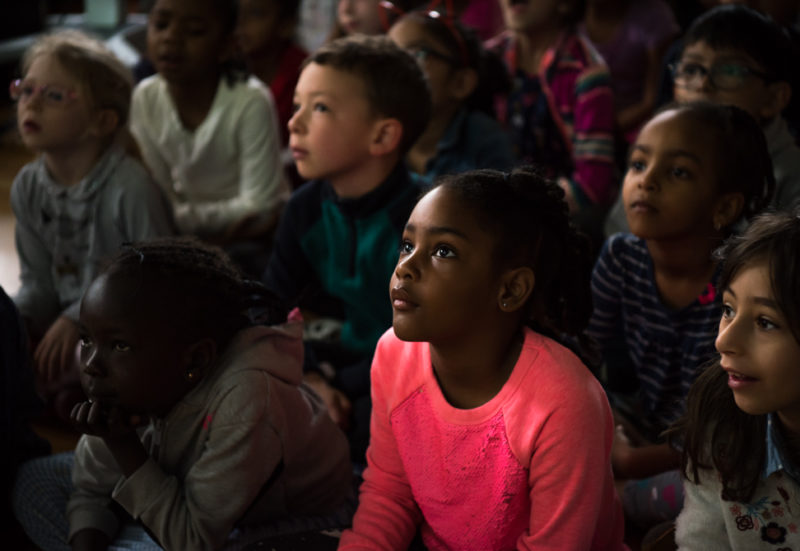 a black female student sits in a crowd of classmates in beautiful light