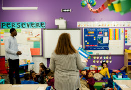 Teacher at front of classroom facing students with back to camera