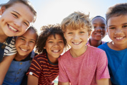 Close up of pre-teen friends in a park smiling to camera