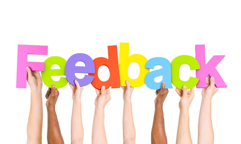 Hands holding up colorful letters to spell the word "feedback"
