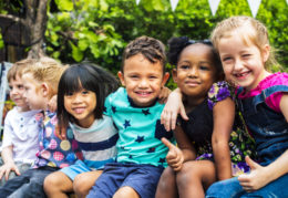 Group of kindergarten kids friends arm around sitting and smilin