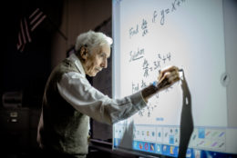 Louis Kokonis works a math problem on the board for his students