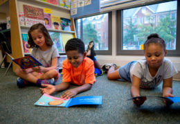 three children reading books together