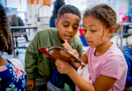 a boy and a girl read a book together about George Washington