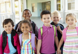 young students with backpacks on holding hands