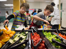 two students serving themselves from the salad bar