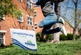 Person mid-air jumping above Spring2ACTion 2018 yardsign