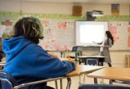 student in class with teacher at smartboard