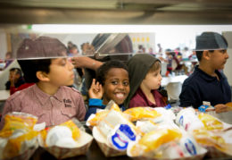 Elementary school boys in cafeteria line with one smiling at the camera