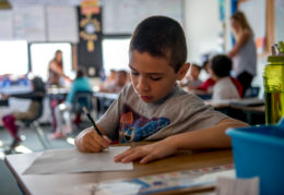 a young male student writes at his desk