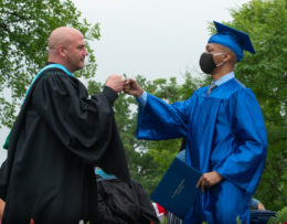 Principal Peter Balas gives a fist bump to a Class of 2021 graduate at the June 2021 graduation ceremony