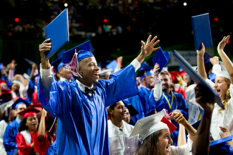 A joyful graduate throws his hands in the air during the ceremony