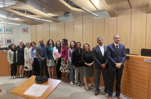 The school board with student representatives and Superintendent Kay-Wyatt gather around the dais and Kay-Wyatt poses with flowers.